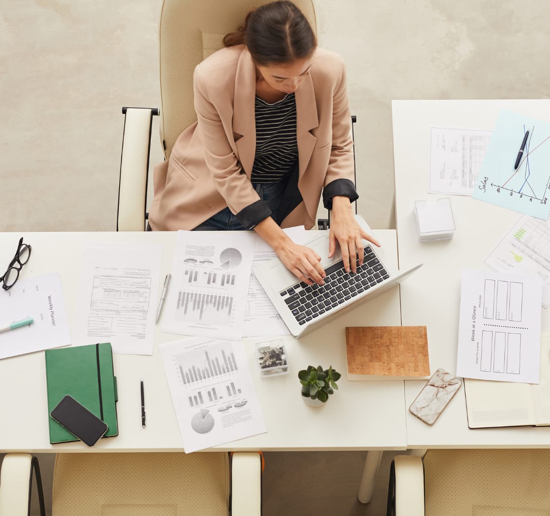 Woman at a desk working on her computer surrounded with work.