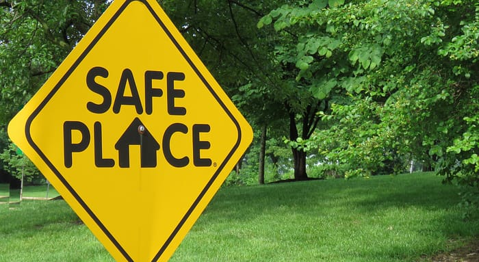 Green park space with a yellow diamond shaped sign with the words 'safe place'